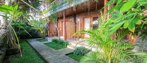A courtyard with a wooden fence, a stone pathway, and lush greenery.