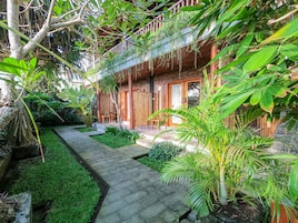 Un patio con valla de madera, sendero de piedra y abundante vegetación.