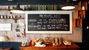 A chalkboard menu listing breakfast and continental options, with a rustic wooden interior and various food items displayed on a counter.