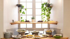 Una mesa de buffet con diversos platos en bandejas, un bol verde y platos apilados.