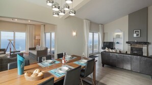Een moderne woonkamer met een eetgedeelte, grote ramen en een open haard.