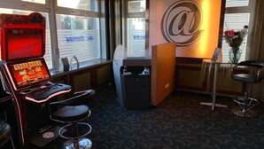Una habitación con una máquina tragamonedas, una recepción con un logotipo '@', una zona de bar con taburetes y una alfombra estampada.