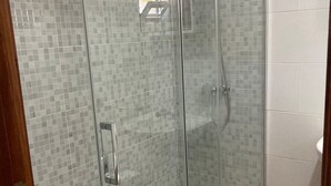 A glass-enclosed shower with a tiled wall and a metal handle. - Pension Porto Carral (Muros)