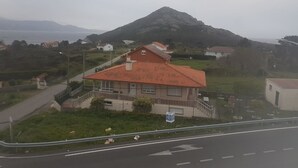 A house with a red roof, a front porch, and a driveway. - Pension Porto Carral (Muros)