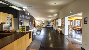 A modern hotel lobby with a reception desk, seating areas, and a view of the dining area. - DJH Garmisch- Partenkirchen - Hostel (Garmisch-Partenkirchen)