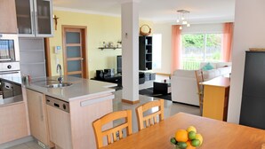 Una cocina moderna con comedor, sillas de madera y un frutero sobre la mesa.