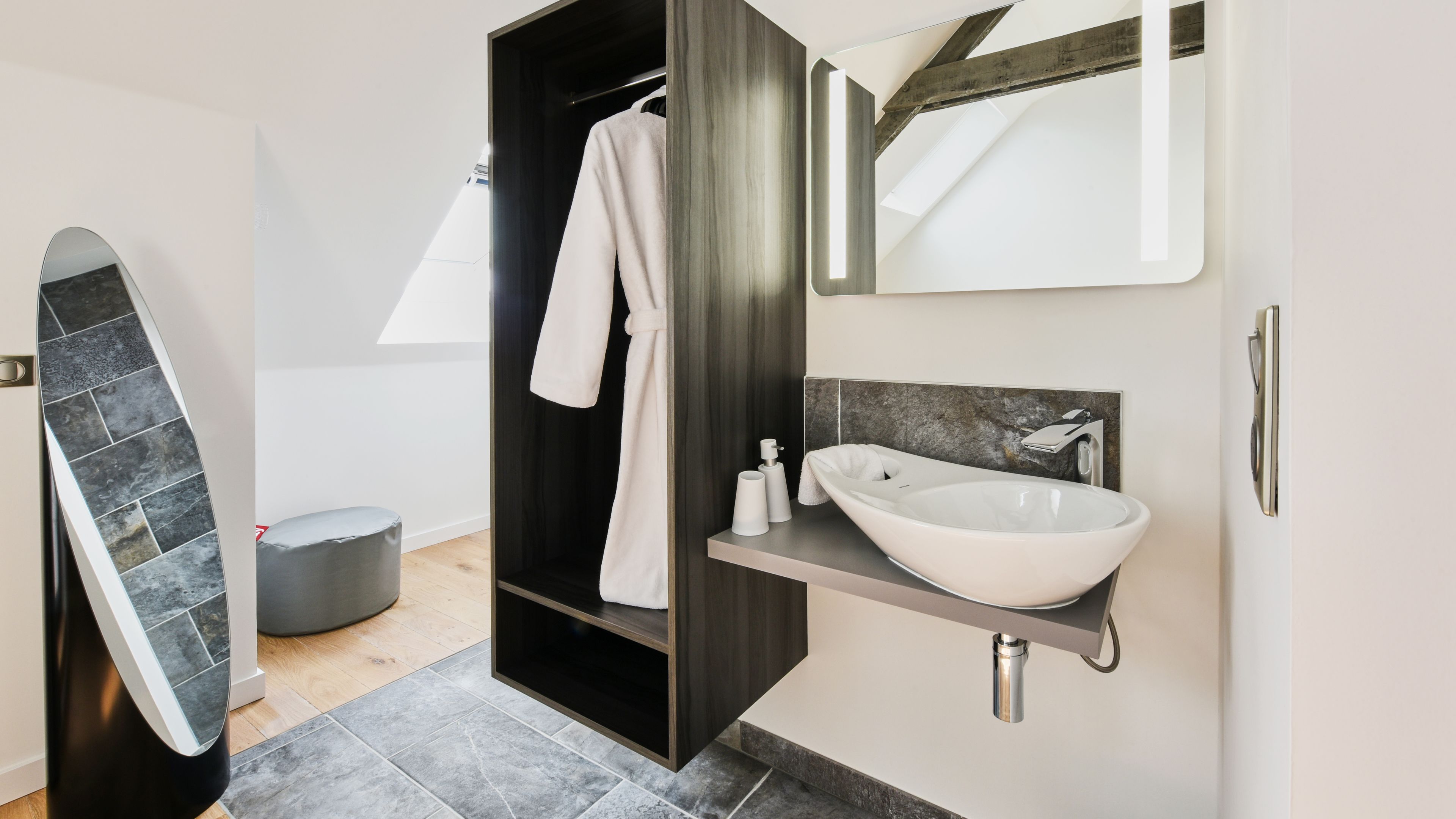 A modern bathroom with a large mirror, a white sink, and a shower area.