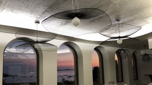 Un interior moderno con ventanas arqueadas, muebles blancos y lámparas de techo de malla metálica negra.