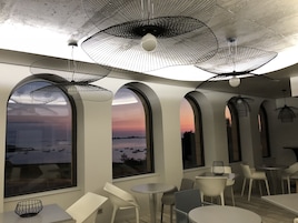 Un interior moderno con ventanas arqueadas, muebles blancos y lámparas de techo de malla metálica negra.