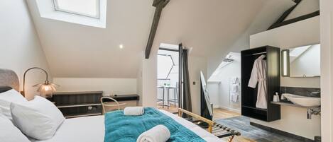 A bedroom with a bed, a bedside table, a lamp, a window, and a view of the outside.