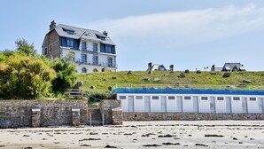 Un edificio costero con varias ventanas y una escalera de piedra que baja a la playa.