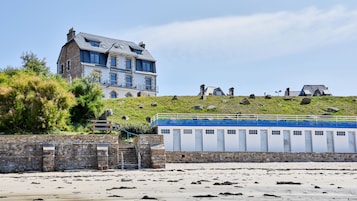 Un edificio costero con varias ventanas y una escalera de piedra que baja a la playa.