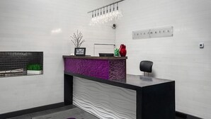 A reception area with a modern design, featuring a black reception desk, a purple accent wall, and a small plant on the left. - Metro Inn (Ranchi)