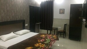 A hotel room with a bed, a desk, a chair, and a wardrobe. - Metro Inn (Ranchi)