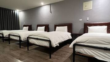 Habitación de hotel con cuatro camas individuales, cabeceros de madera y una pared gris oscuro.