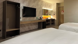 Une chambre d’hôtel équipée d’un grand téléviseur à écran plat, d’une coiffeuse en bois avec un miroir, d’un lavabo et d’un lit.