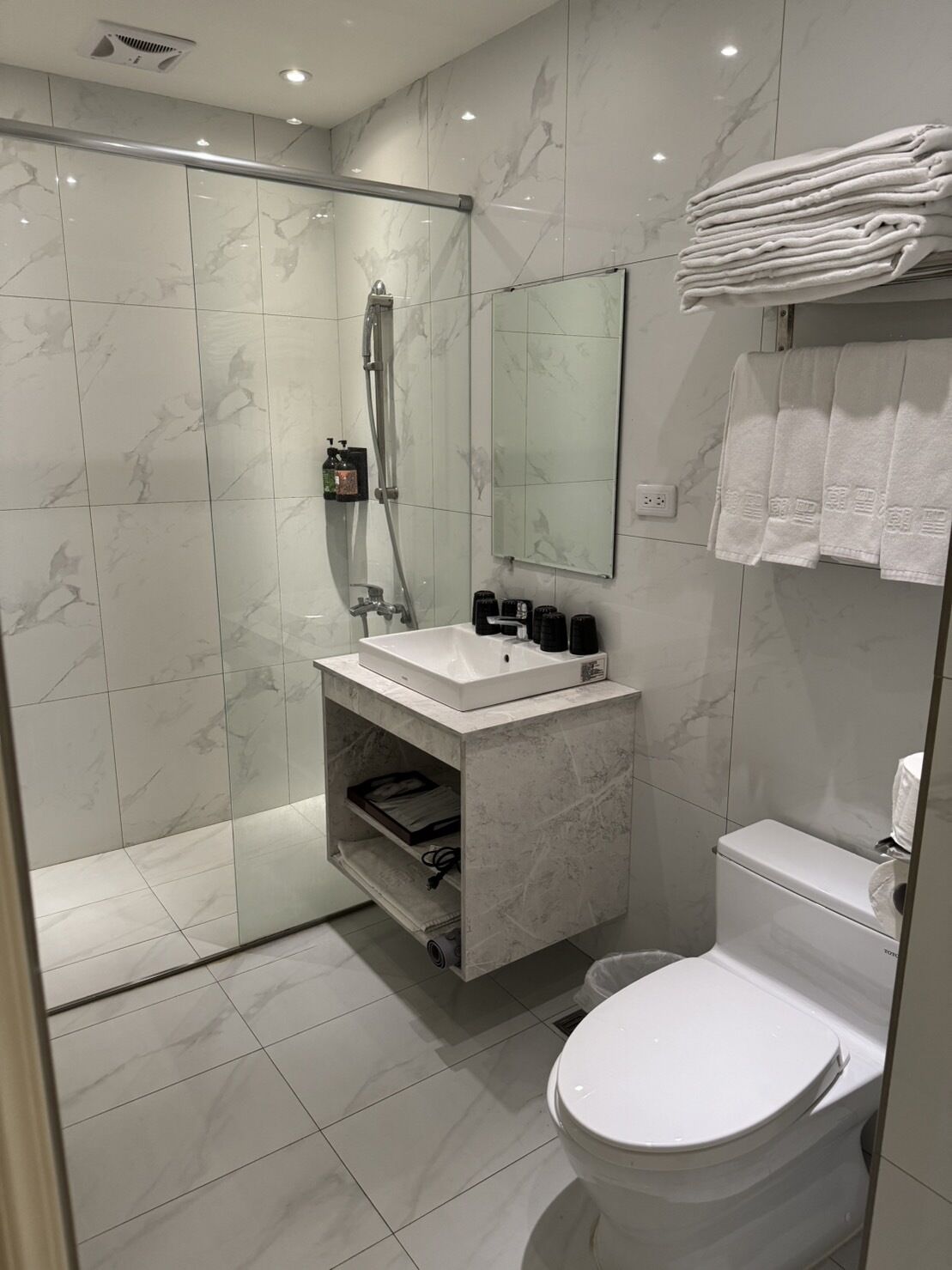 A modern bathroom with a glass-enclosed shower, a white sink, and a toilet.