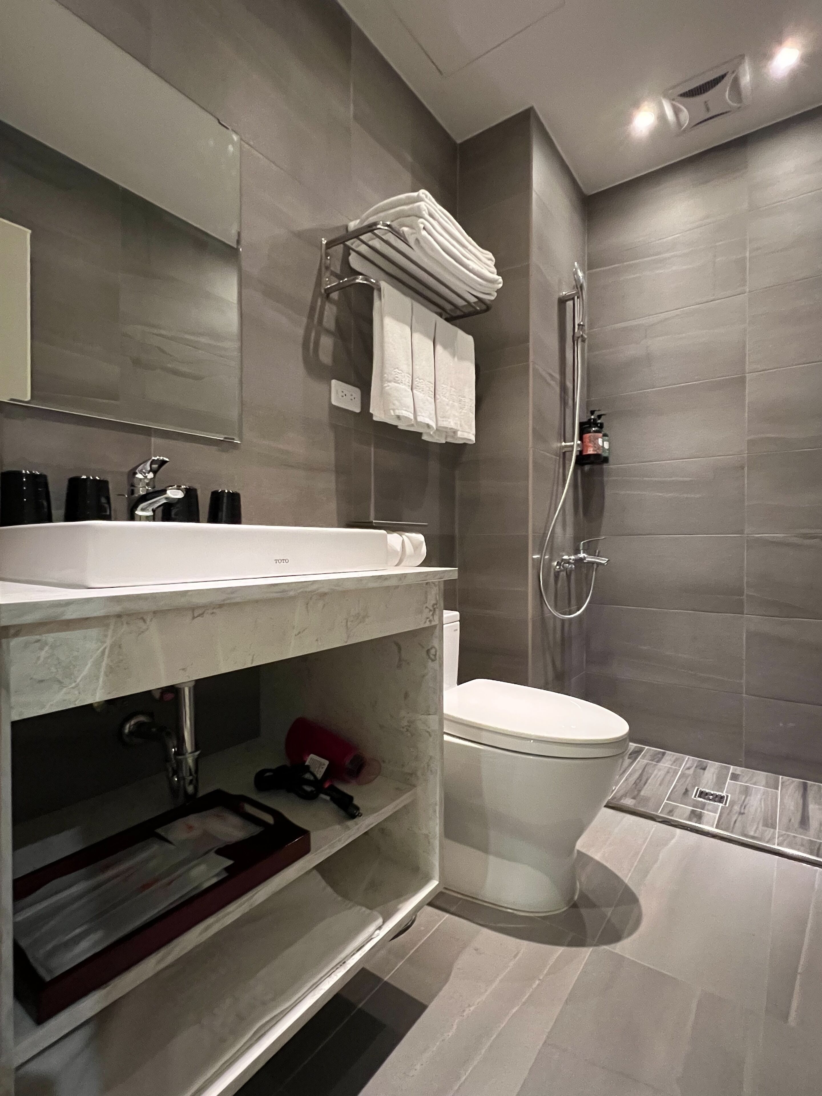 A modern bathroom with a white sink, a toilet, and a shower.