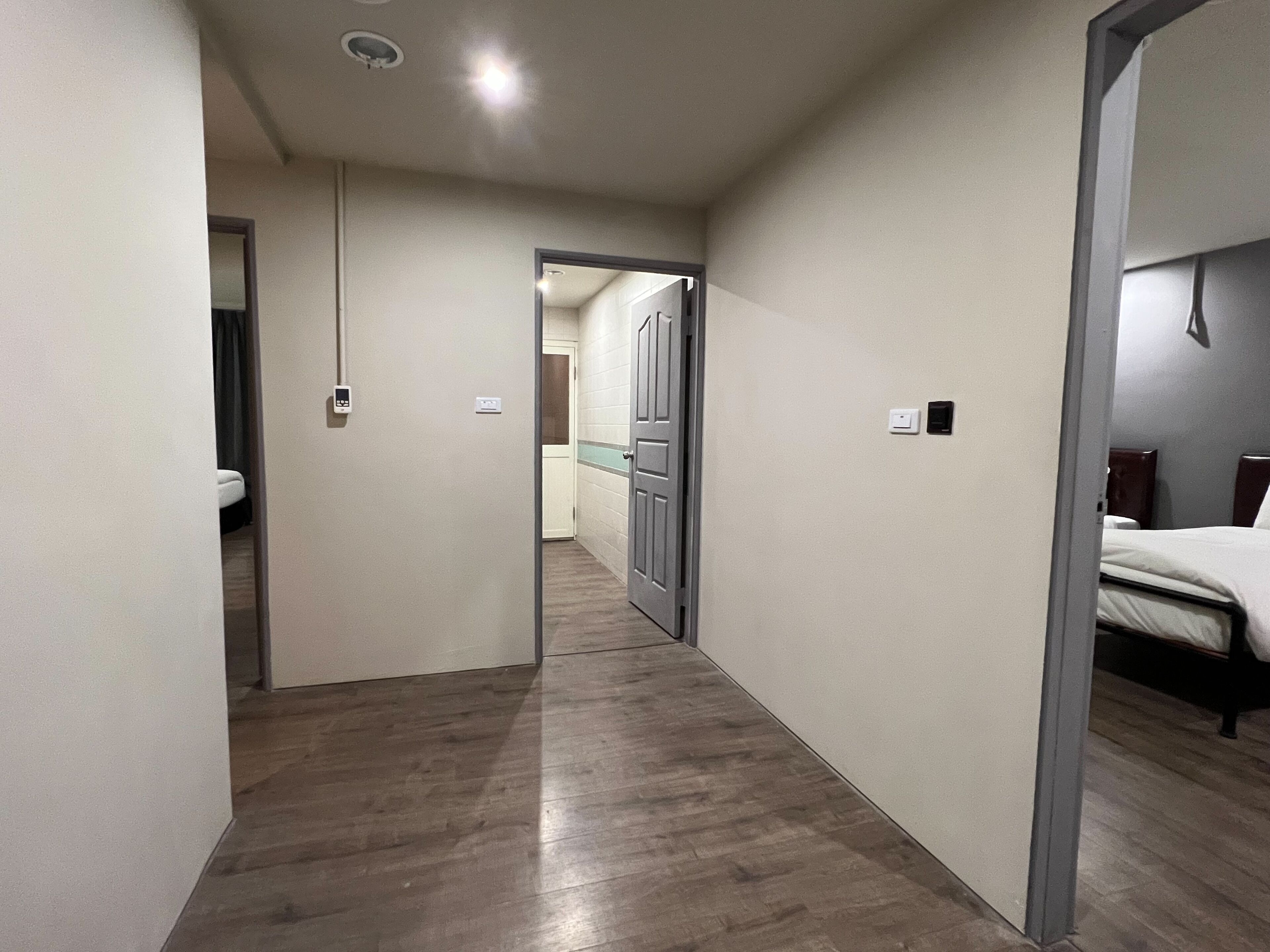 Un pasillo de hotel con suelo de madera, una cama a la derecha y un baño a la izquierda.