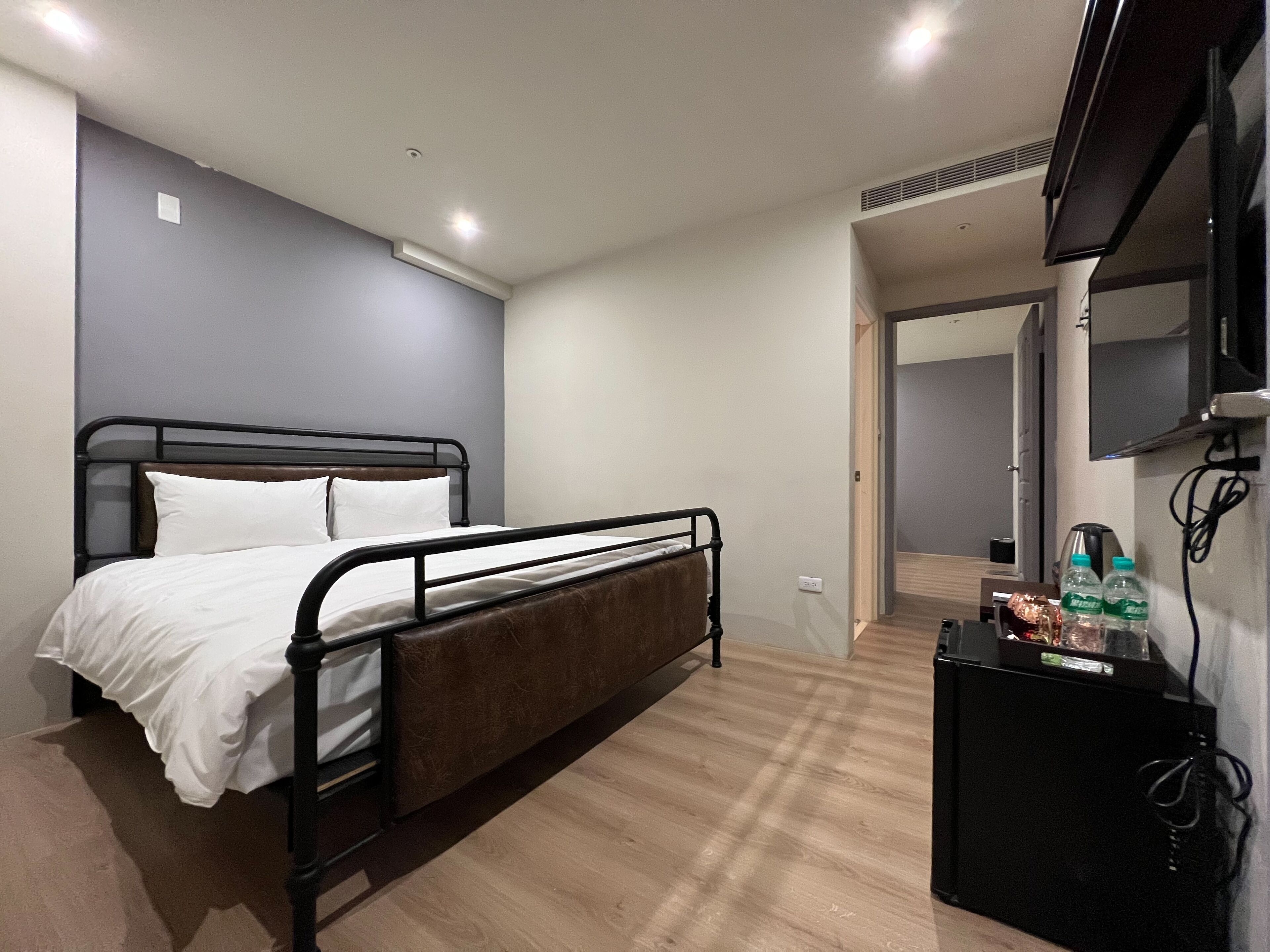 Un dormitorio con una cama individual, un escritorio pequeño con una computadora y un televisor montado en la pared.