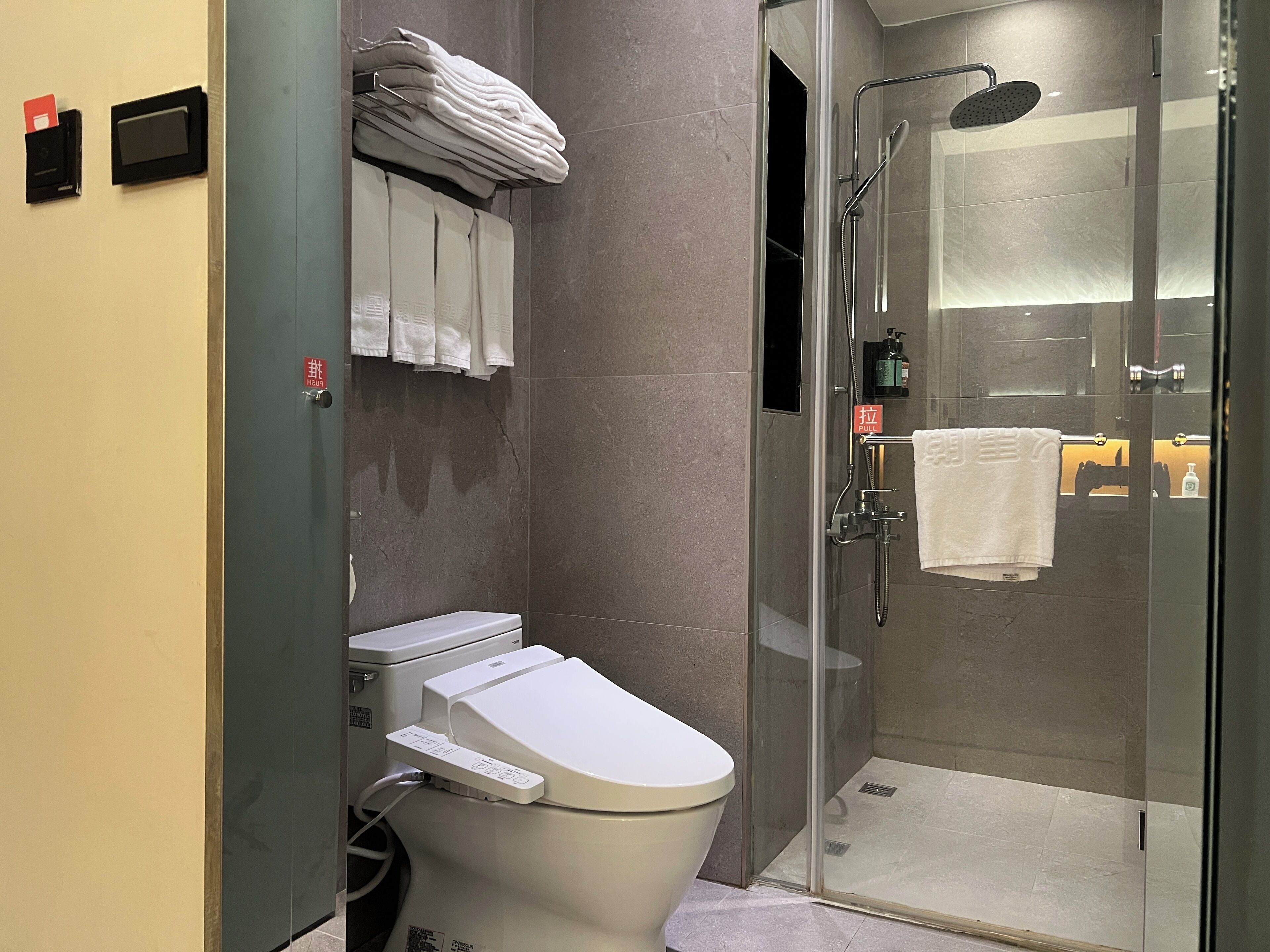 Une salle de bain moderne équipée de toilettes, d’une douche à parois de verre et d’un porte-serviettes.