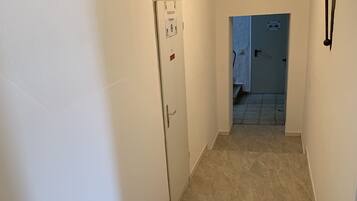 Un pasillo estrecho con una puerta a la izquierda y una escalera que sube a otra habitación.