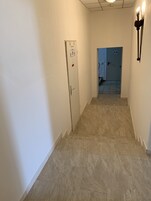 Un pasillo estrecho con una puerta a la izquierda y una escalera que sube a otra habitación.