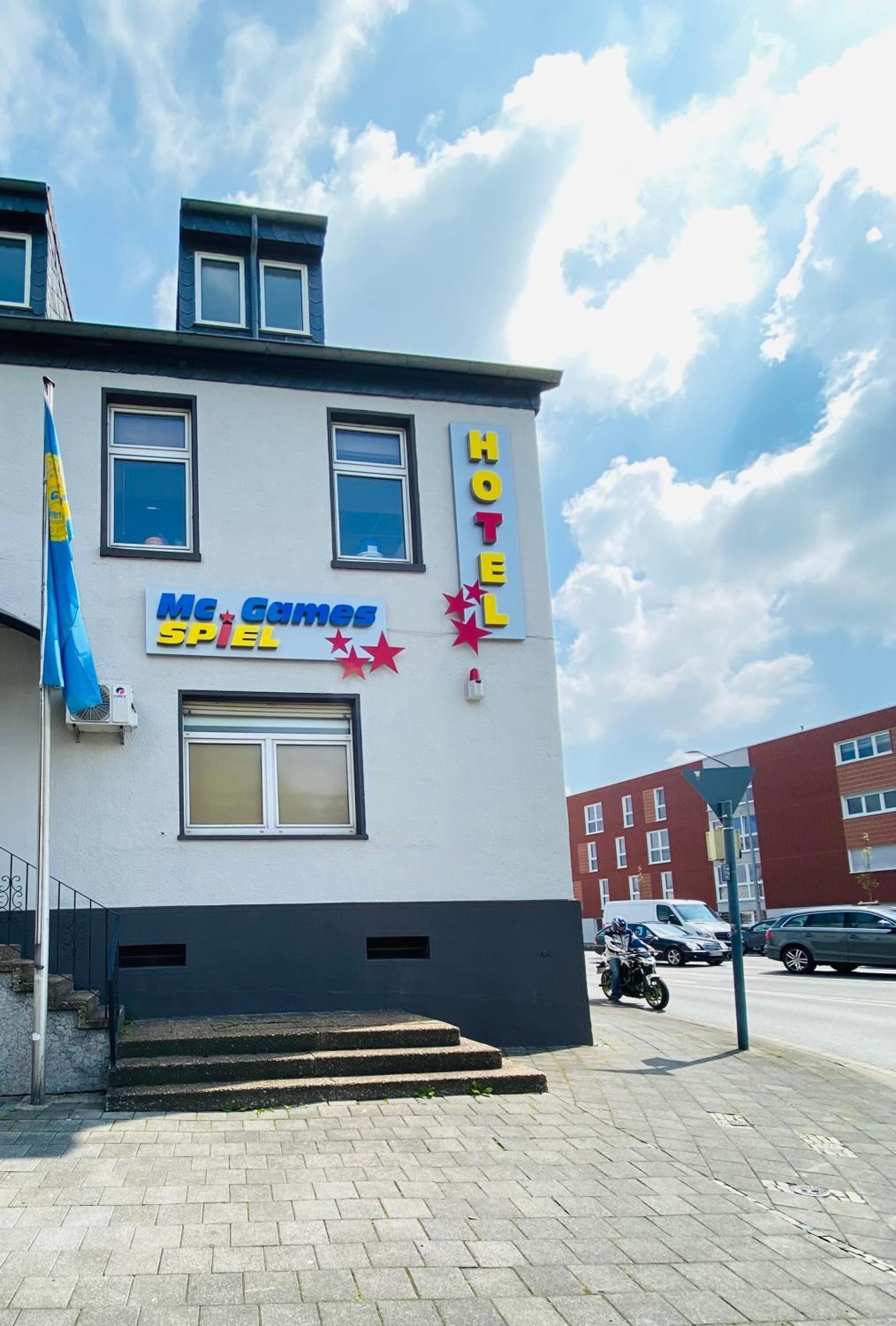 Ein Hotel mit einem Schild für "MC Games Spiel" und einer Fahnenstange mit einer blauen Flagge.