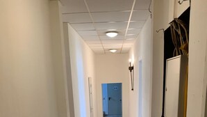 Un pasillo con suelo de baldosas, paredes blancas y una puerta al final.
