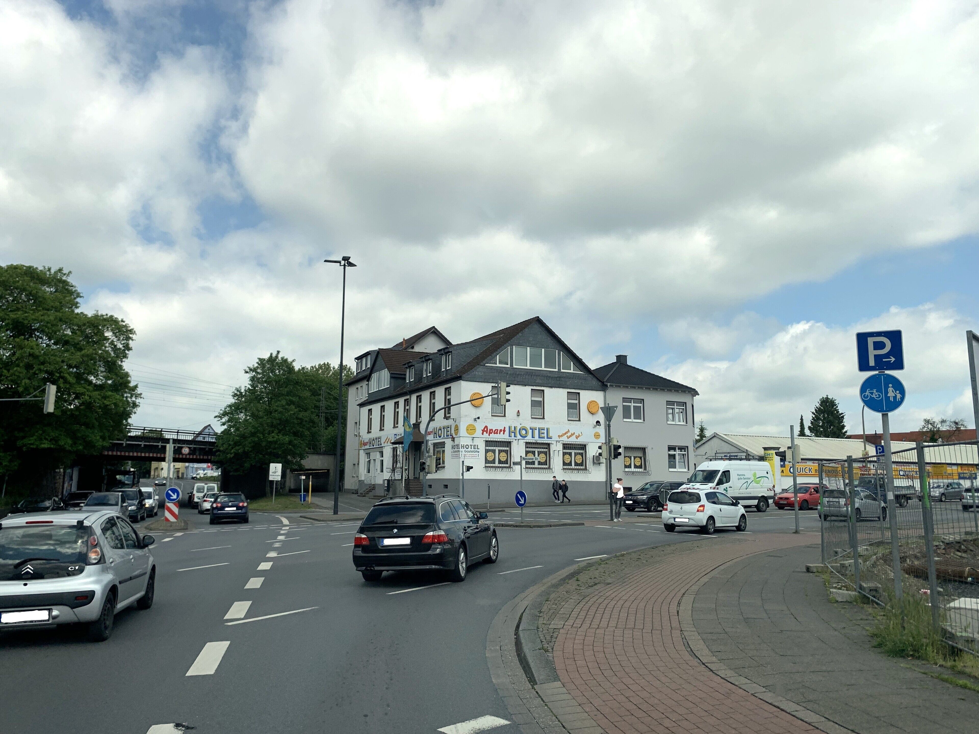 A street view with a hotel, a parking sign, and a pedestrian crossing.