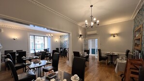 A dining area with multiple tables and chairs, a chandelier, and a patterned wall.