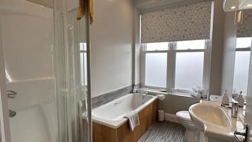 A modern bathroom with a glass shower enclosure, a freestanding bathtub, a vanity with a sink, and a toilet.