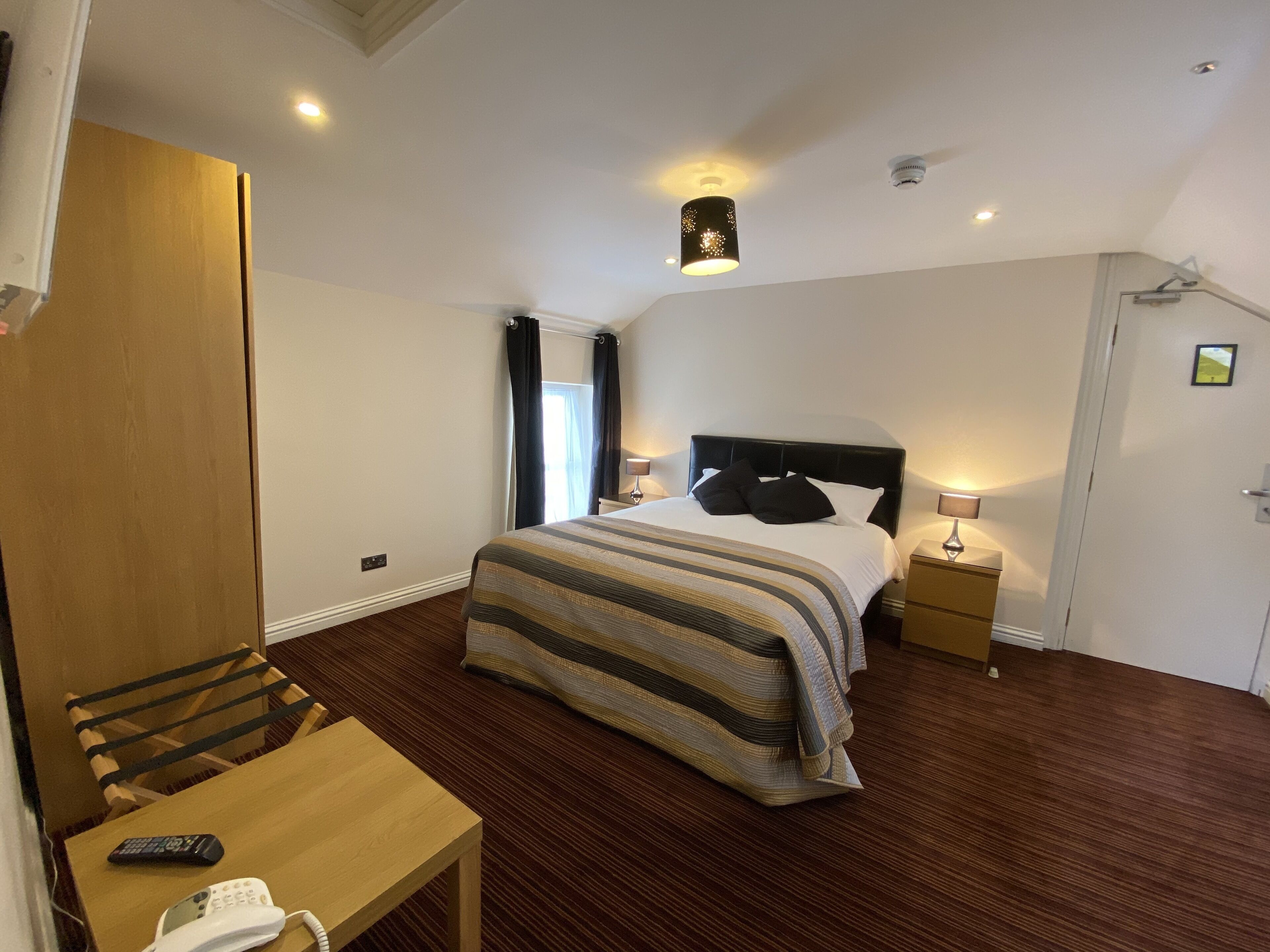 A hotel room with a bed, bedside tables, a desk, and a chair.