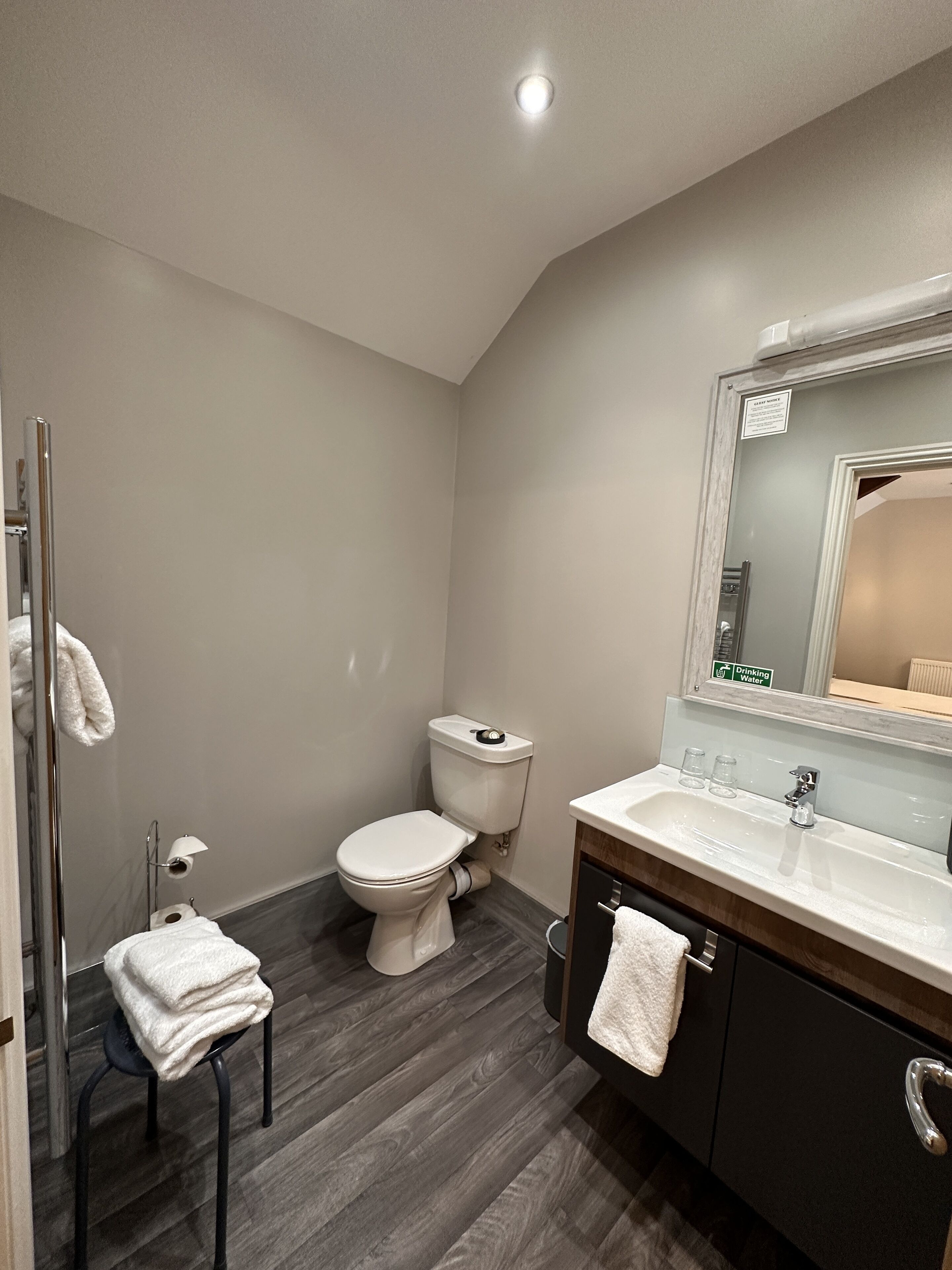 Un baño moderno con inodoro, lavamanos y espejo.
