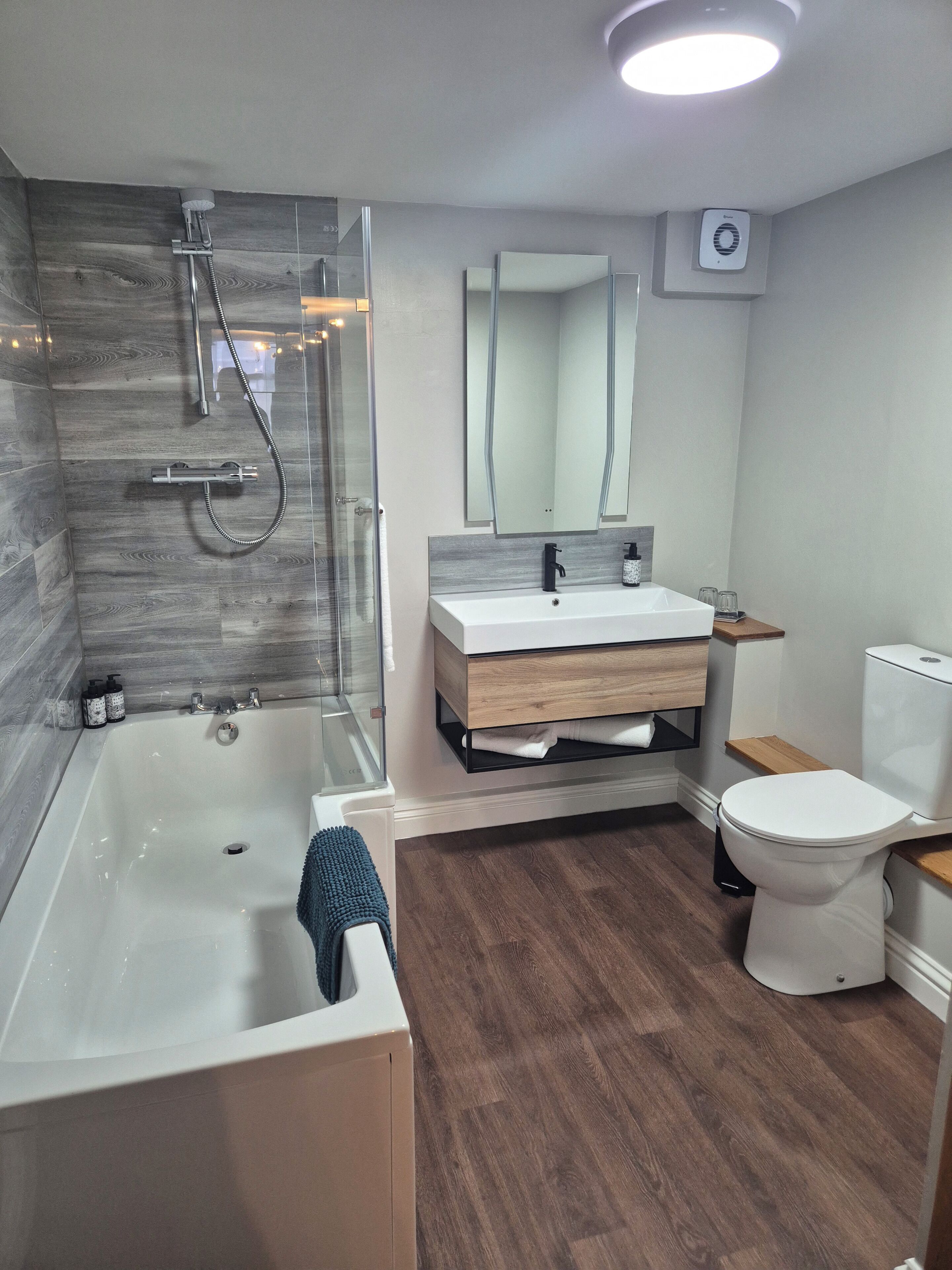 Un baño moderno con bañera, ducha, lavabo con espejo y retrete.