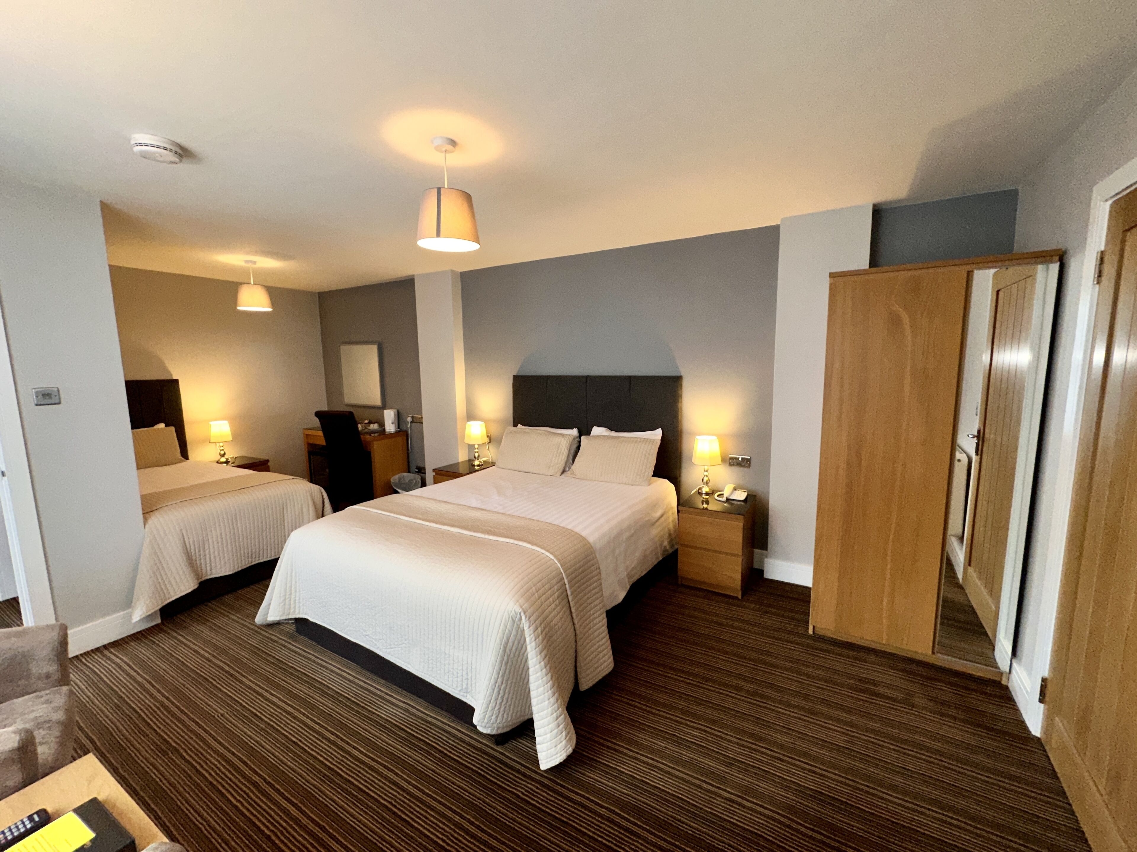 Une chambre d’hôtel avec deux lits, une armoire, un bureau et une chaise.