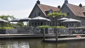 Une propriété située au bord de l’eau, dotée d’un quai, d’un espace extérieur aménagé et d’une rangée de maisons aux toits recouverts de tuiles rouges.