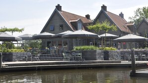 Un restaurant situé au bord de l’eau, avec une terrasse et des parasols.