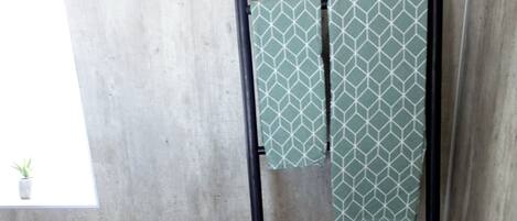 Quarto com parede de concreto, escada de metal, um banquinho e um balde marrom.