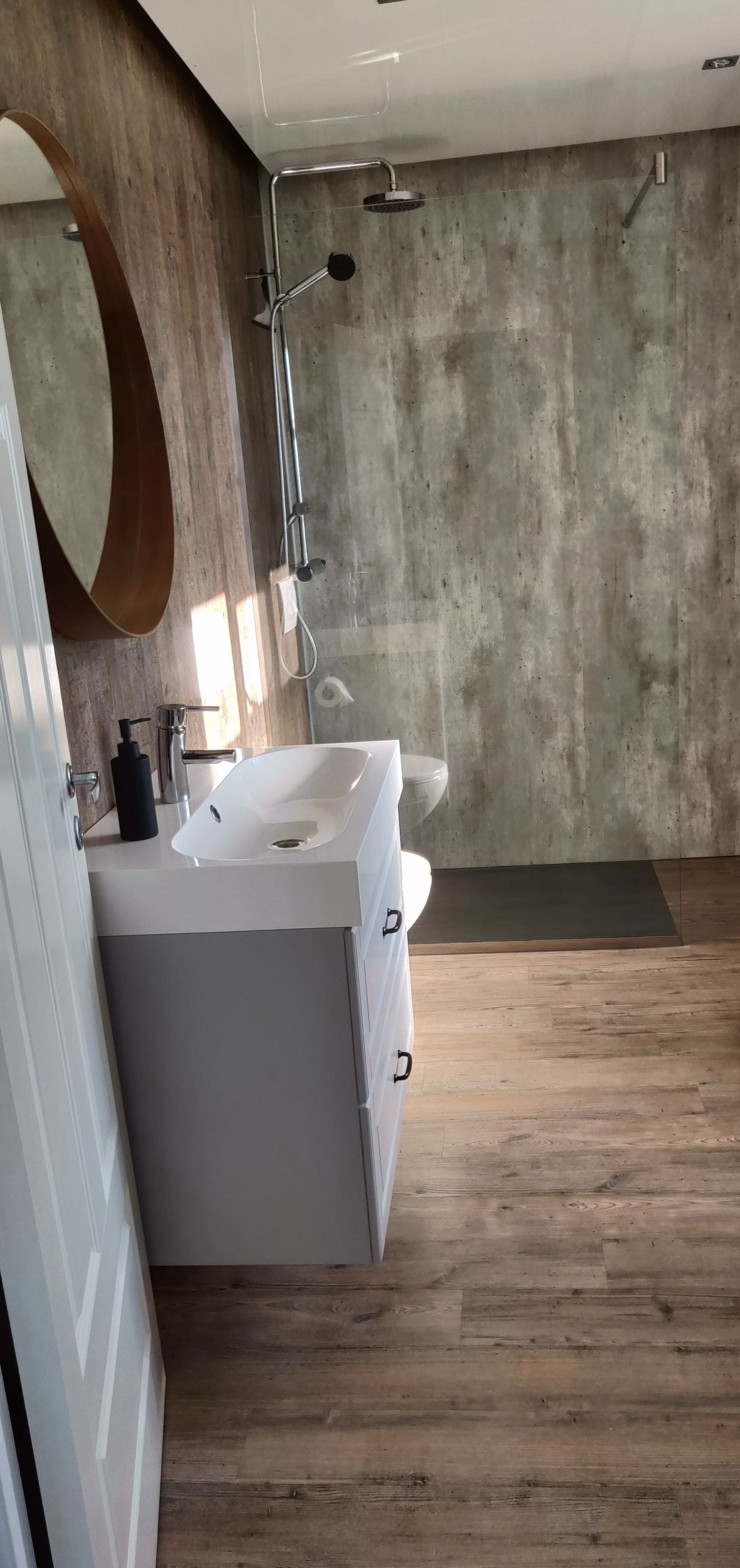 Une salle de bain moderne avec un grand miroir, un lavabo blanc et un espace douche.