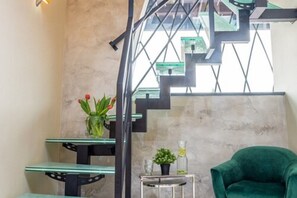 A staircase with glass railings and a green chair. - Norweska Dolina Luxury Resort (Szklarska Poreba)