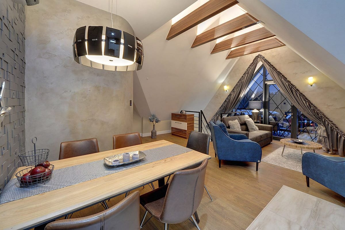 A modern loft with a dining area, seating, and a view through a large window.
