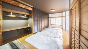 A traditional Japanese-style room with tatami flooring, sliding doors, and a low wooden bed. - Zerogravity koniya clubhouse (Setouchi)
