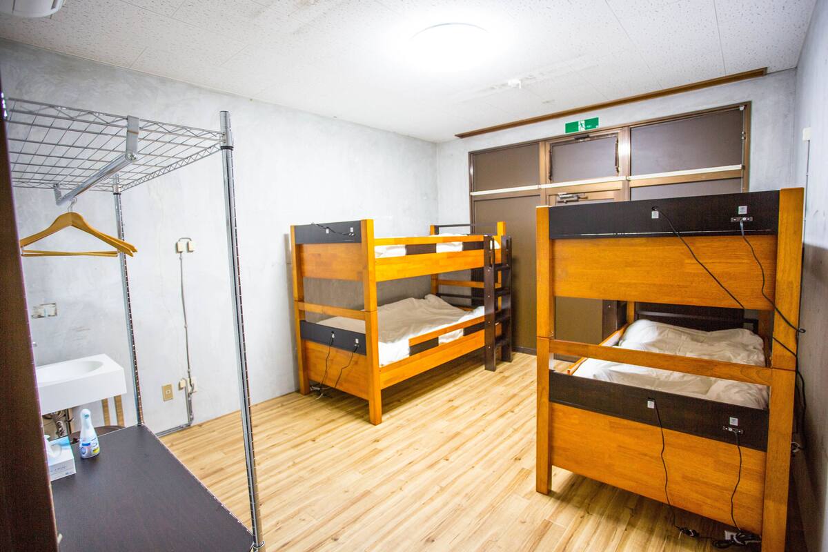 A dormitory room with bunk beds, a sink, and a drying rack.