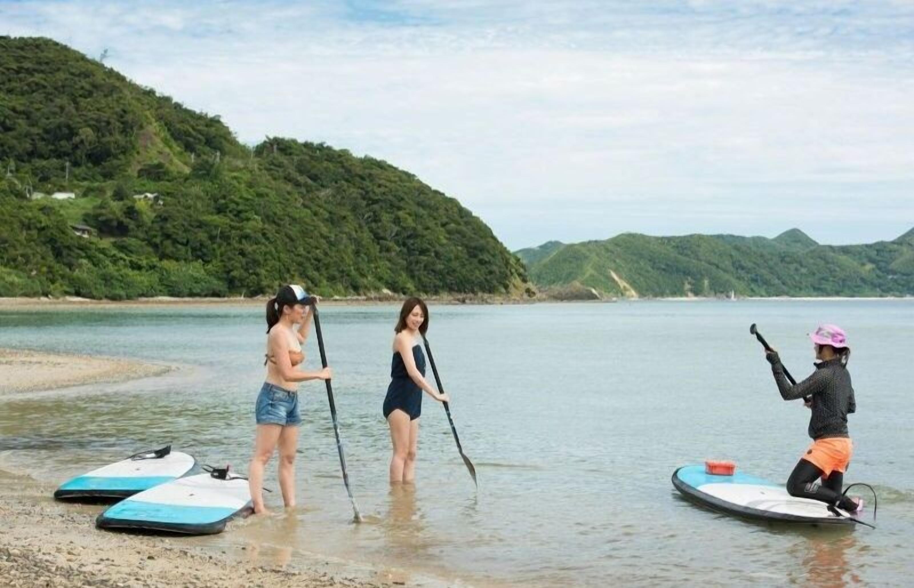 Three people on paddleboards in a calm body of water with hills in the background.