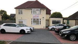 A two-story building with a sign for 'Oxford B&B'. There are three cars parked in front. - Oxford Bed and Breakfast (Kidlington)
