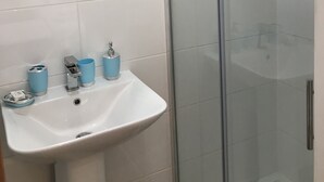A bathroom with a white sink, a mirror, and a glass shower enclosure. - Oxford Bed and Breakfast (Kidlington)