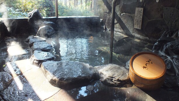 A hot spring area with stone steps leading into the water, a wooden barrel, and a wooden fence in the background. - Hananoyado Fukuya (Hakone)