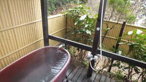 A wooden deck with a hot tub, bamboo fence, and greenery in the background. - Hananoyado Fukuya (Hakone)