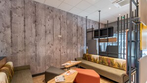 A modern interior with a wooden wall, a sofa with a colorful cushion, a small table with a magazine, and a bench.